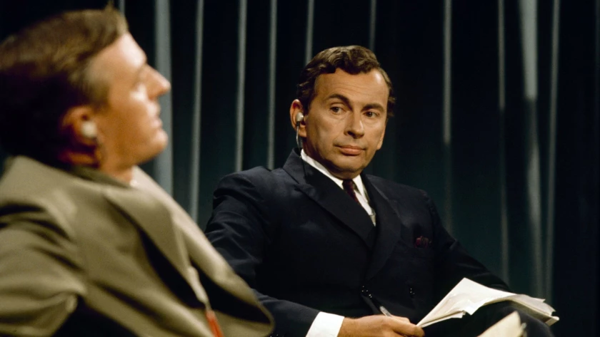 Una persona sentado con un traje de color negro
Descripción generada automáticamente con confianza media